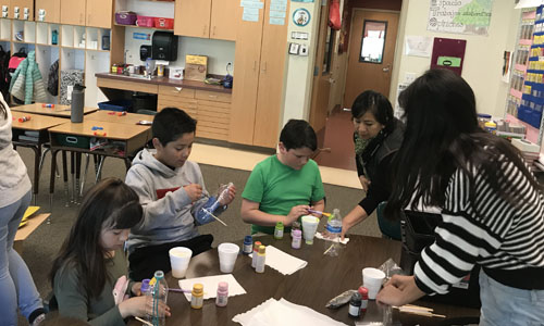 students painting plastic bottles 